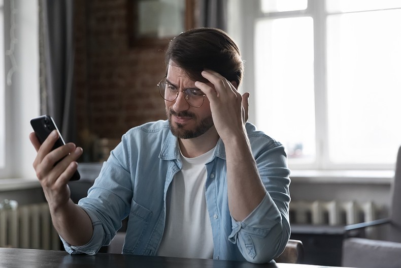 Concerned Man Looking at Smartphone